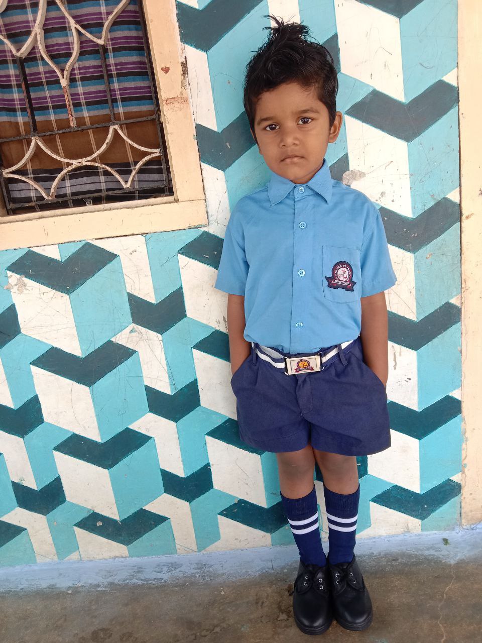 a boy standing in front of a wall with a blue and white design